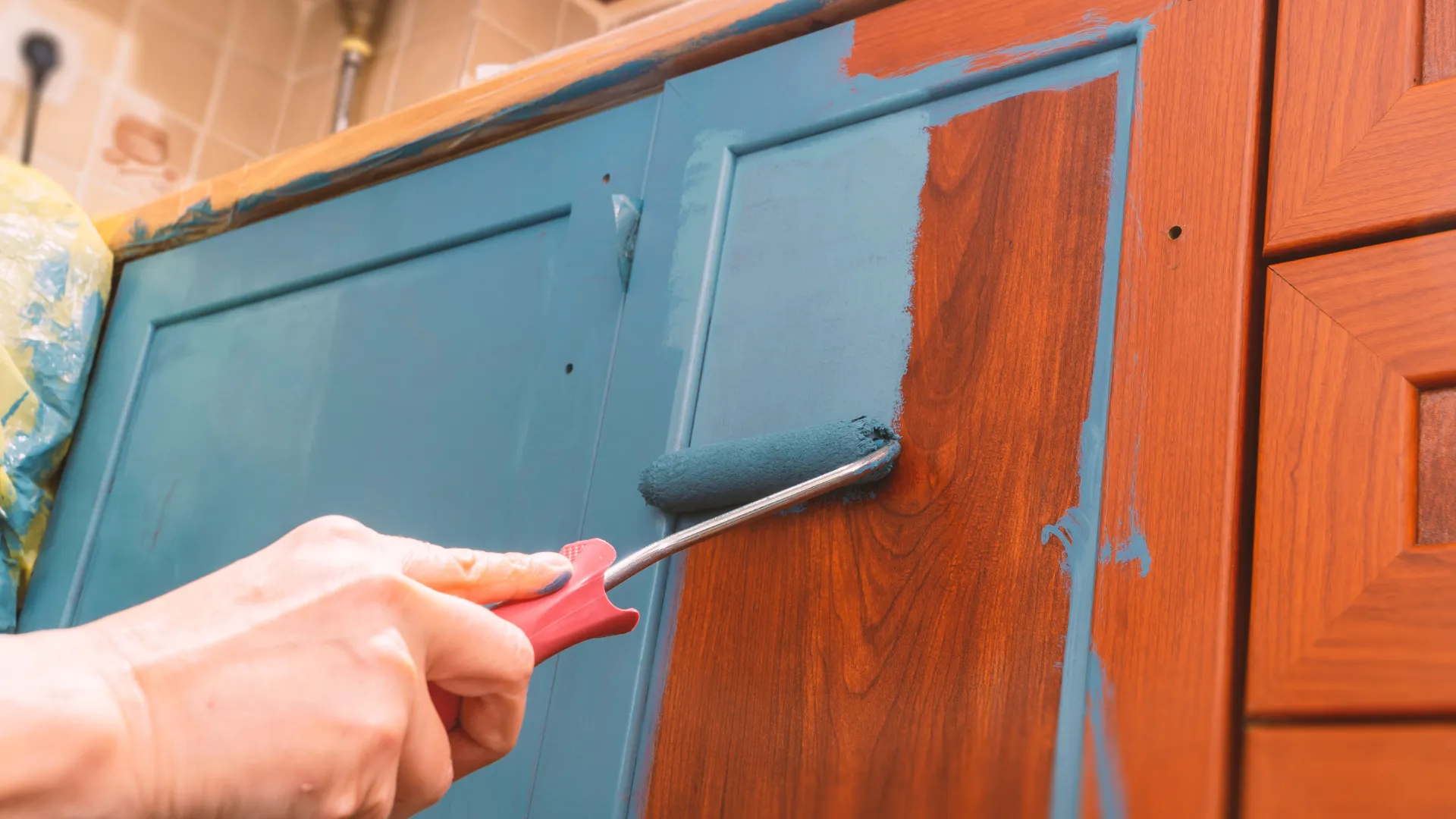 painter painting a kitchen cabinet in blue colour